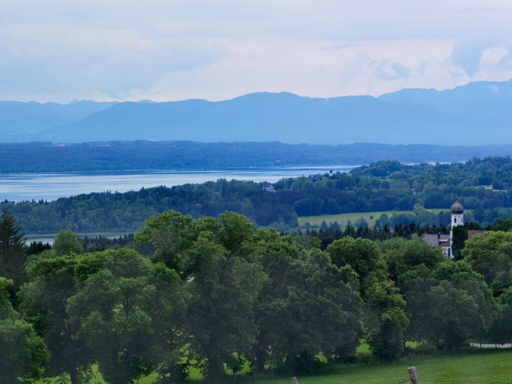 Maximaler Ausblick auf der Ilkahöhe mit Starnberger See, die Alpen und der St. Nikolaus Kirche